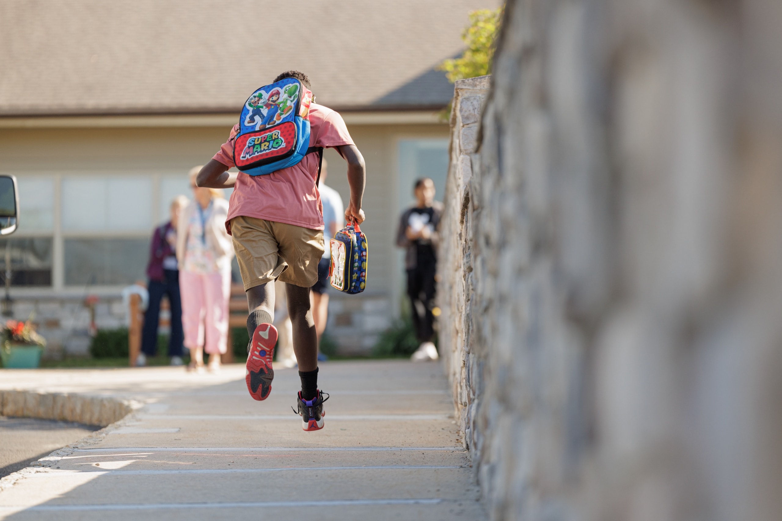 Student running outdoors with a backpack